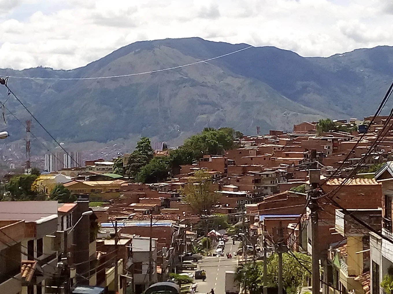 Panoramic view of a red-brick neighborhood in a Latin American city with mountains in the background.