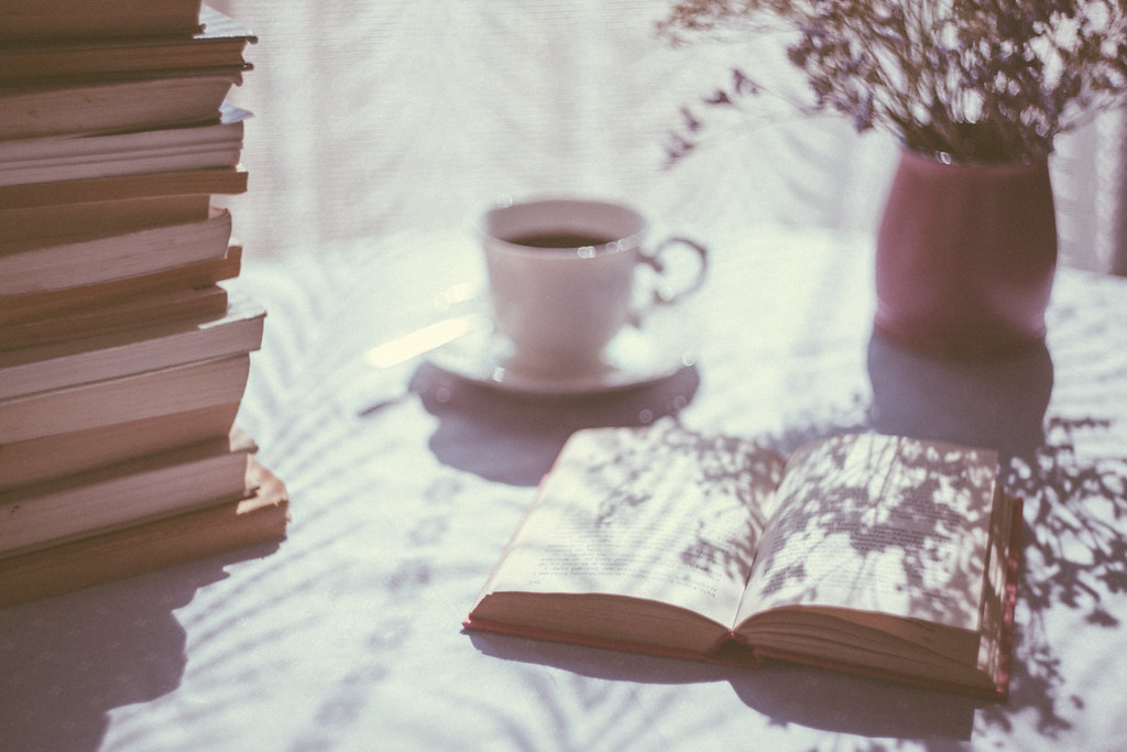 Coffee cup next to an open book on a table